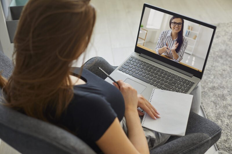 Remote work concept. Young woman talking to boss or colleague on laptop computer from home. Businesswoman communicating with client online